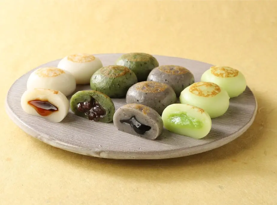 白、よもぎ、黒ごま、うぐいすの4種類の餡入り焼きまんじゅうが皿に綺麗に並んでいる様子